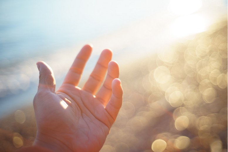 Hand reikt naar zacht zonlicht als symbool voor afstemmen op de Aquarius-frequentie Hand reikt naar zacht zonlicht als symbool voor afstemmen op de Aquarius-frequentie